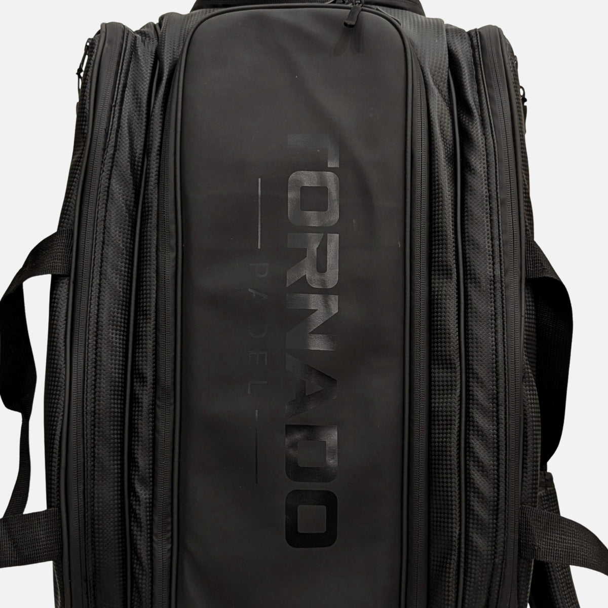 A black Tornado padel tennis bag with a large, tonal black logo printed vertically on the front panel, shown against a light gray background with 2 racket space