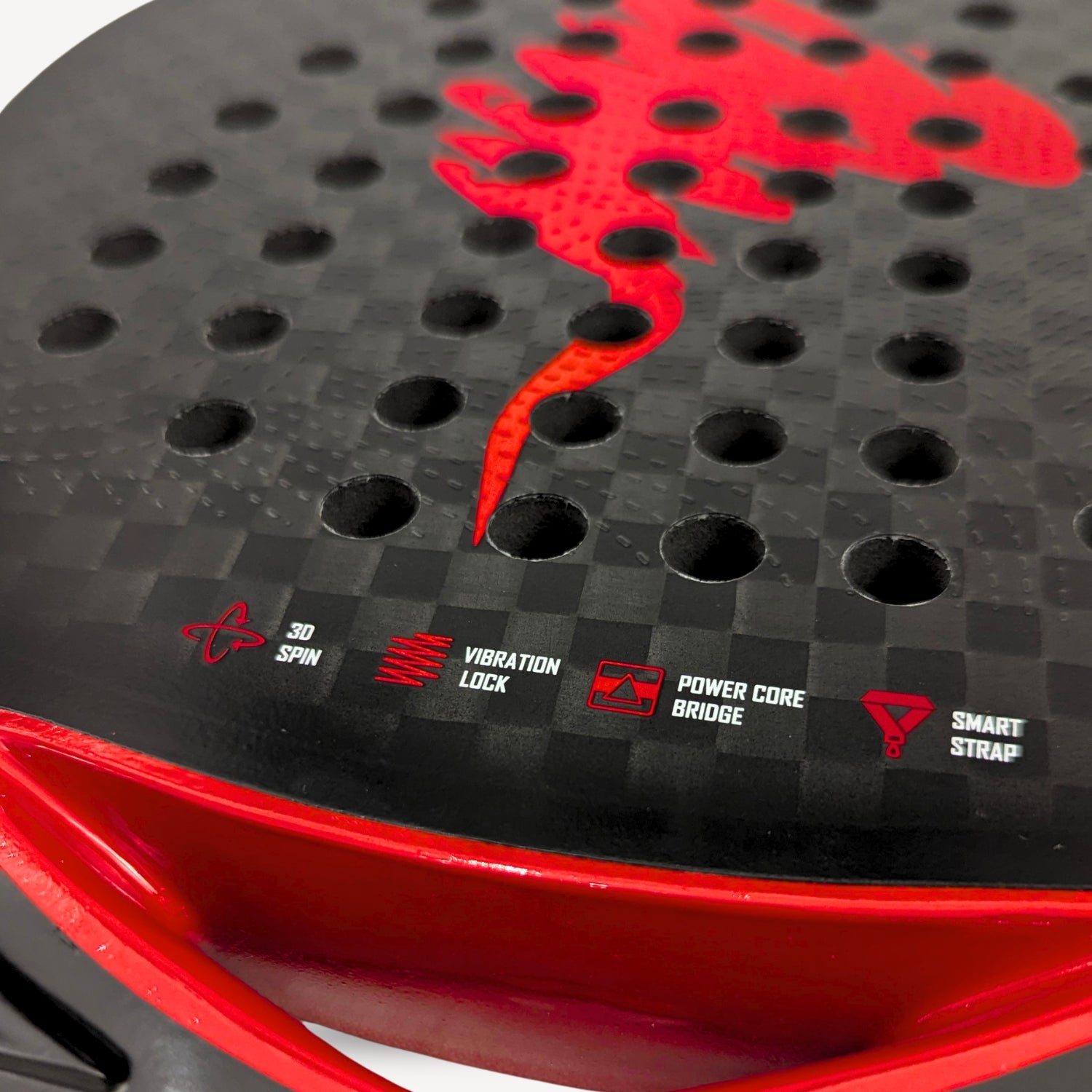 Close-up of a red and black sports padel racket with branding and text on a dark background