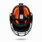 Back view of a cricket helmet with orange interior, black cage, and red exterior on a white background.