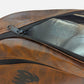Close-up of a brown faux-leather bag with a black zipper and a black mesh pocket, showing a metallic silver interior lining. padel racket cover