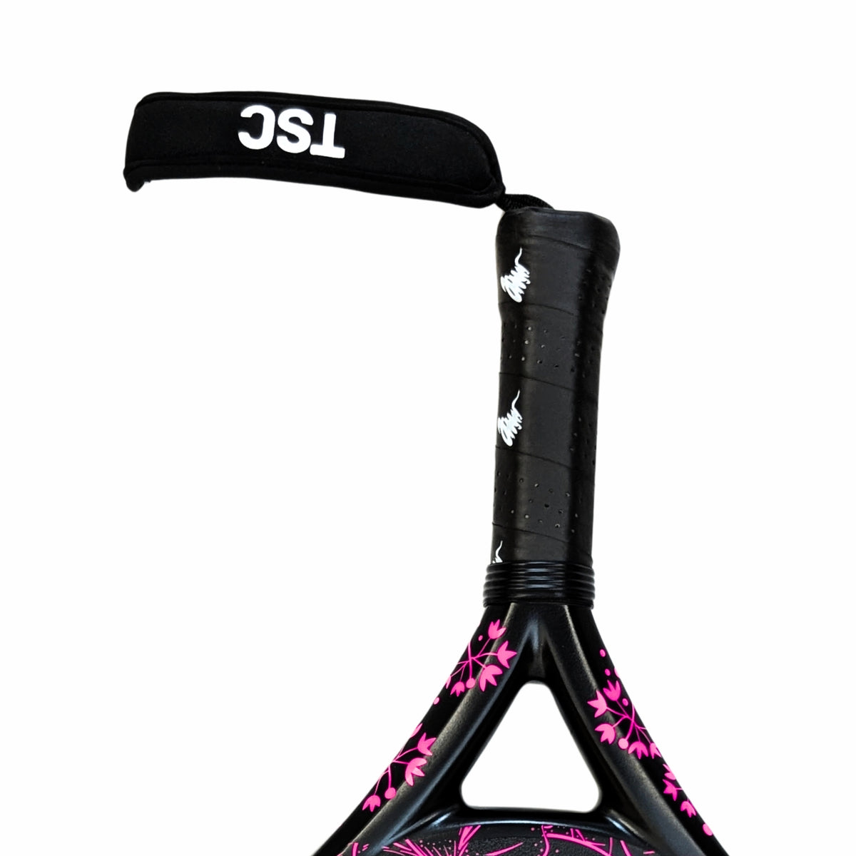 Close-up of a paddle padel racket handle with a black TSC wrist strap, black textured grip tape, and a black frame decorated with pink floral patterns, on a white background.