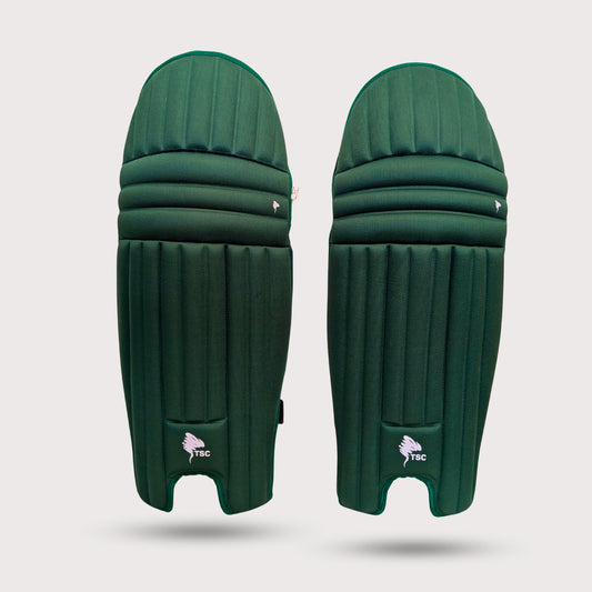 Pair of green cricket molded pads leg guards on a light gray background