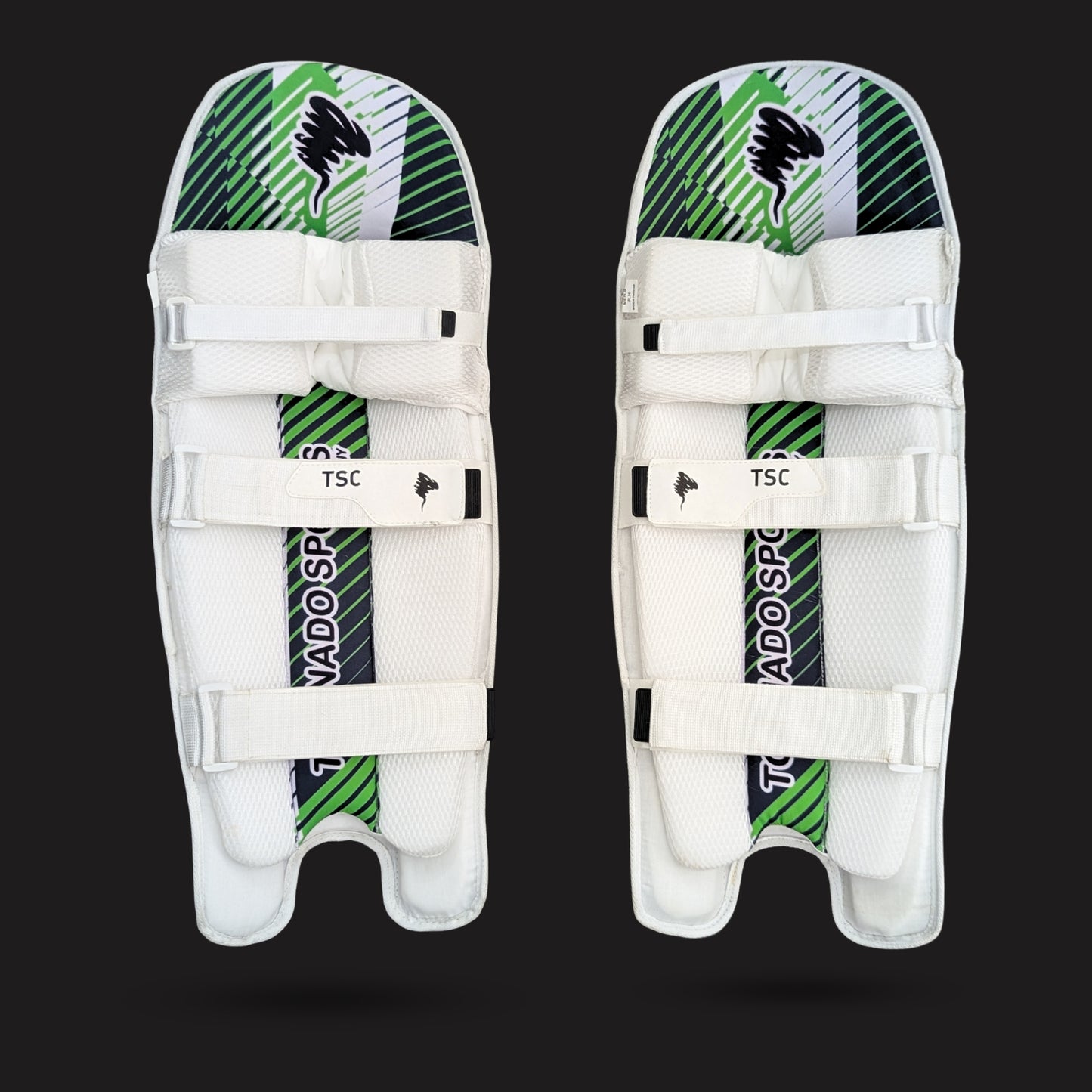 Pair of white cricket leg guards with green and black patterns on a black background