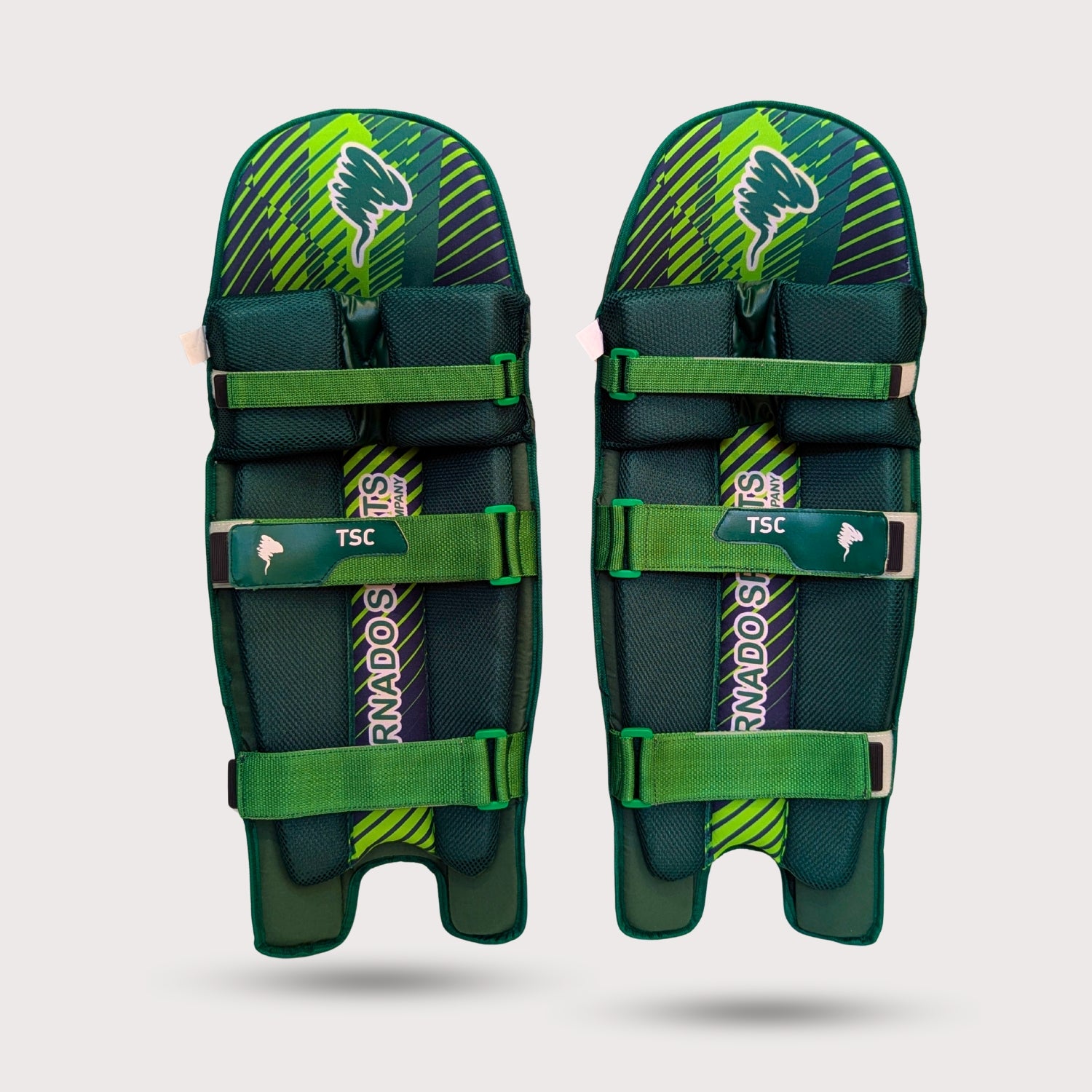 Pair of green and black Cricket pads with TSC branding on a light gray background