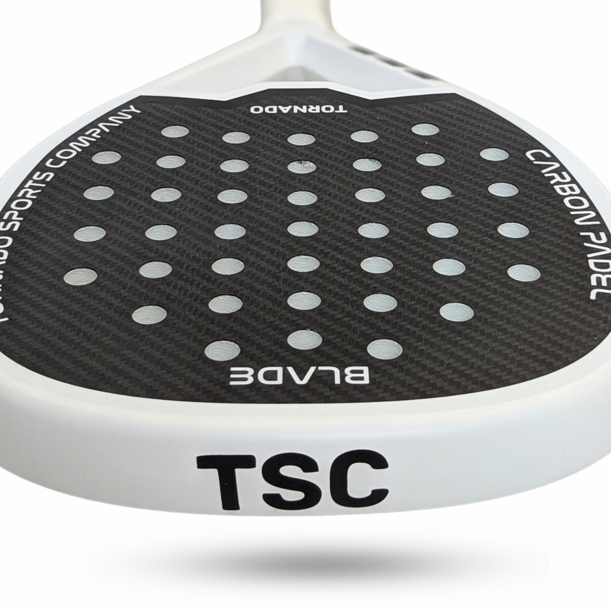 Close-up of a TSC Blade paddle tennis racquet head featuring a black carbon fiber pattern with circular cutouts and white branding text, on a white background.